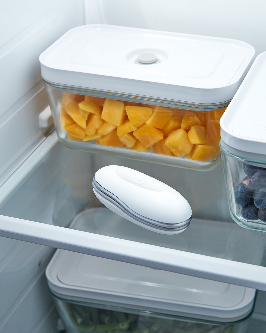 Der Cooling Roller liegt in einem Kühlschrankfach, dahinter eine Dose mit Mango und daneben eine Dose mit Blaubeeren.“