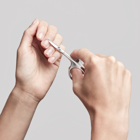Anwendung einer ZWILLING Premium Nagelhautschere aus rostfreiem Edelstahl an der Nagelhaut des linken Mittelfingers.