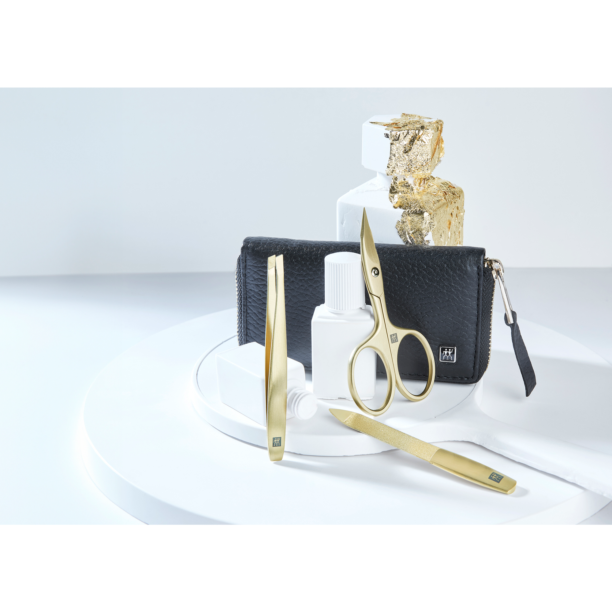 Darstellung eines ZWILLING Premium Maniküre Sets 3tlg. umgeben von artifiziellen Betonobjekten, veredelt mit Blattgold.