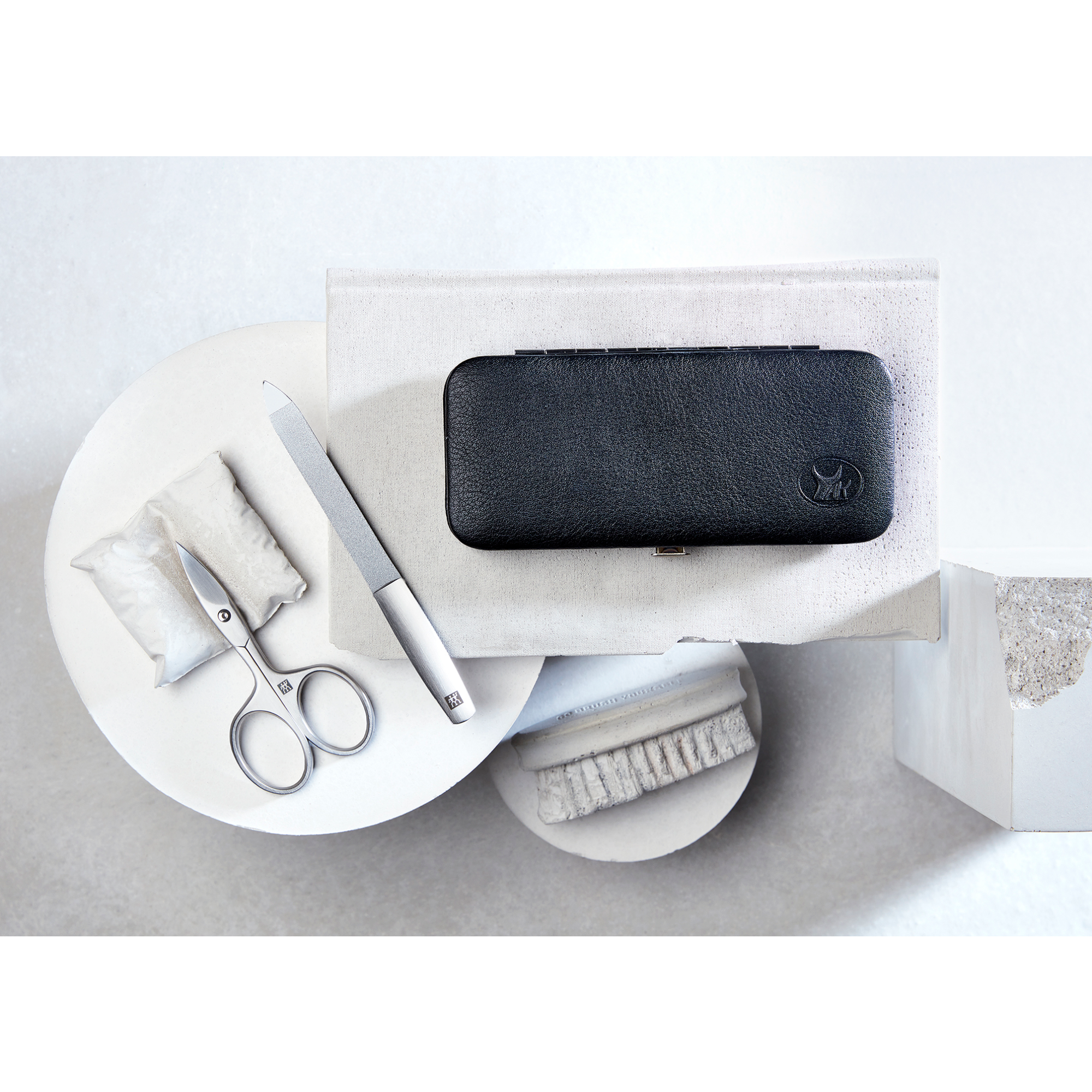 Darstellung eines ZWILLING Premium Maniküre Sets 5tlg. umgeben von artifiziellen Betonobjekten.