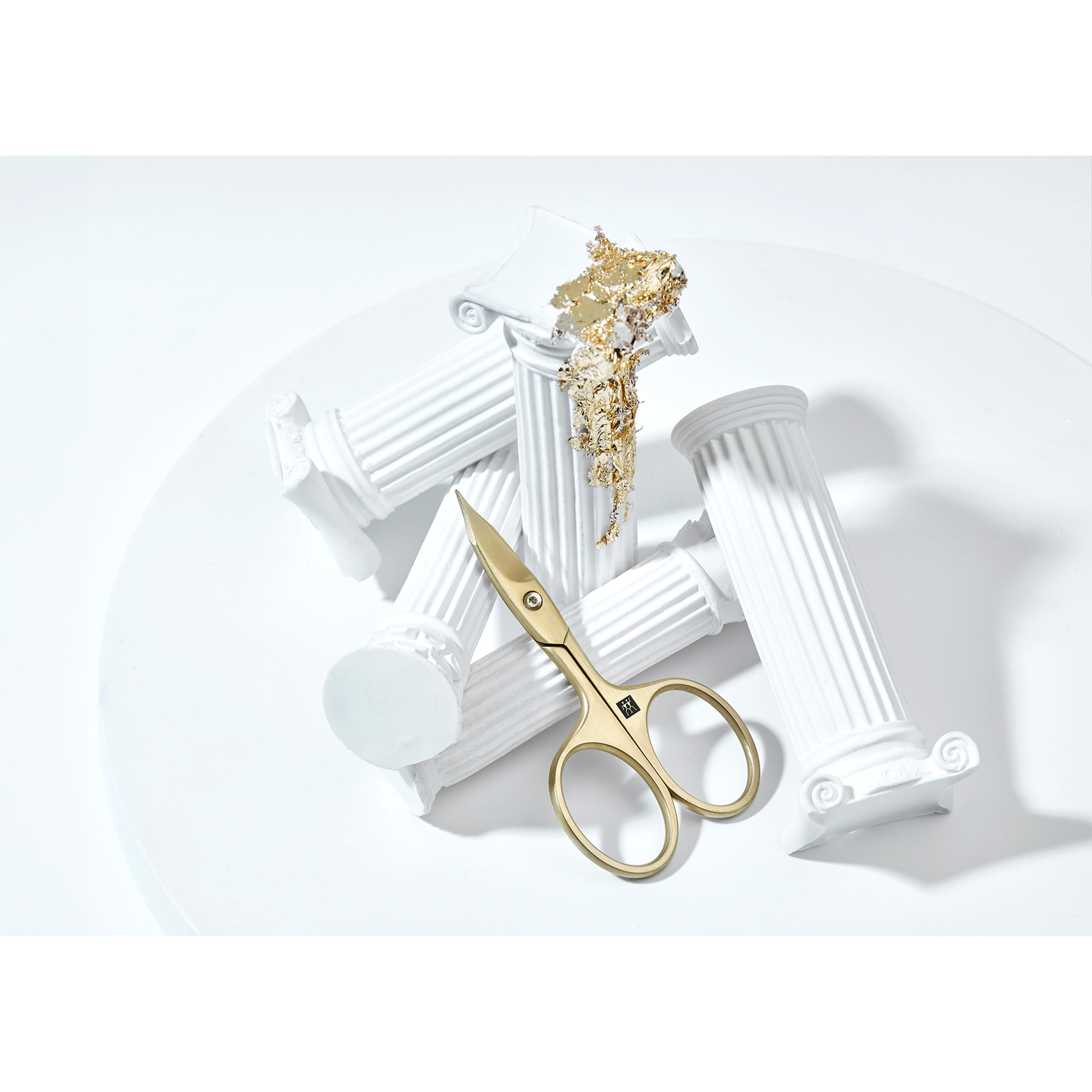Sehr hochwertige Darstellung der ZWILLING Premium Nagel- und Nagelhautschere inmitten von artifiziellen Marmorsäulen mit Blattgold.