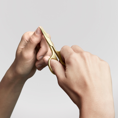 Anwendung einer ZWILLING Premium  Nagel- und Nagelhautschere in Gold  am linken Daumennagel.