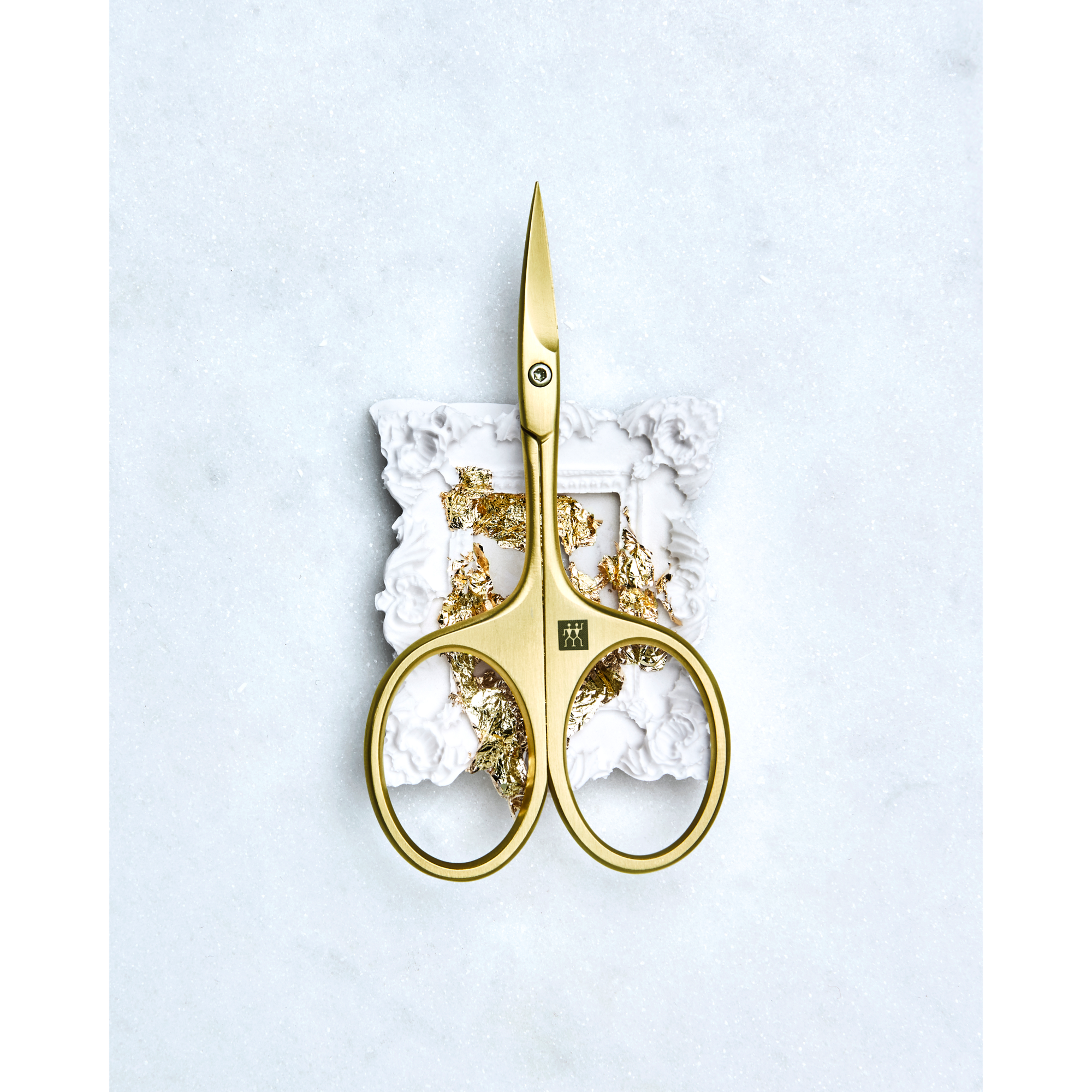 Sehr hochwertige Darstellung der ZWILLING Premium Nagelhautschere inmitten eines artifiziellen Rahmens mit Blattgold.