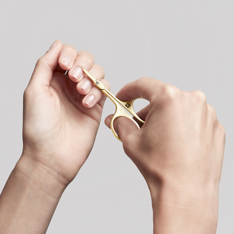 Anwendung einer ZWILLING Premium Nagelhautschere in Gold an der Nagelhaut des linken Mittelfingers.
