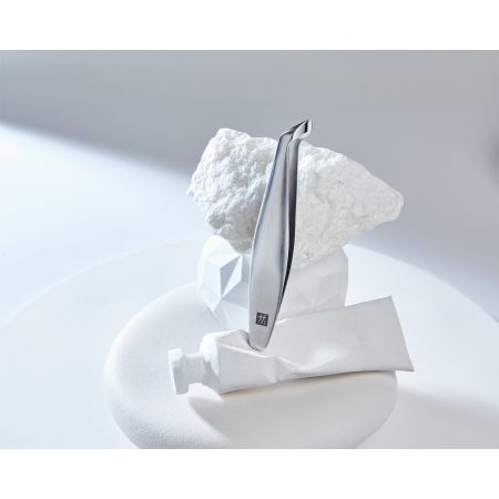 Darstellung des ZWILLING Premium Nagelhautschiebers aus rostfreiem Edelstahl positioniert auf diversen, artifiziellen Objekten.
