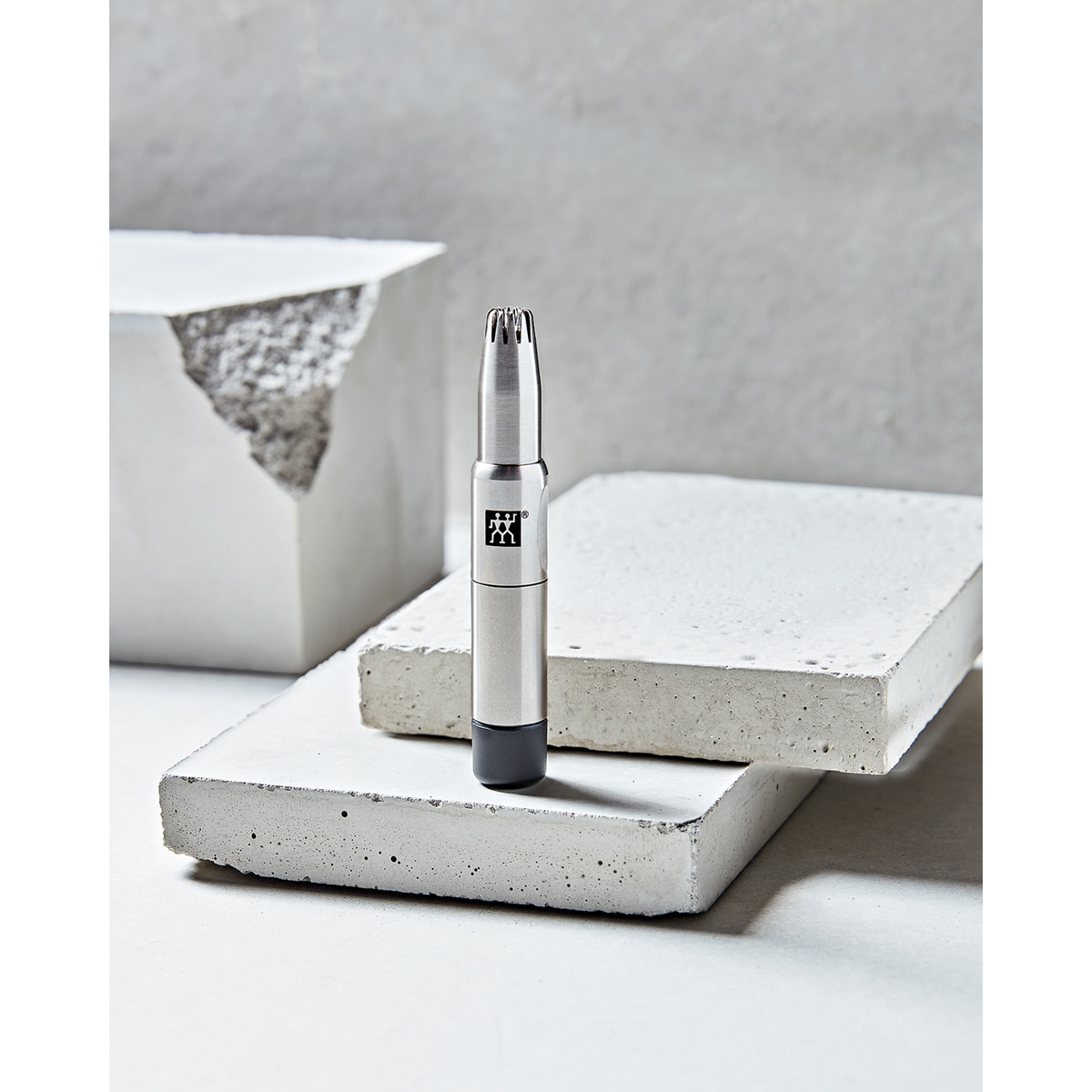 Darstellung des ZWILLING Premium Nasen- und Ohrenhaartrimmer aus rostfreiem Edelstahl auf Betonplatten.