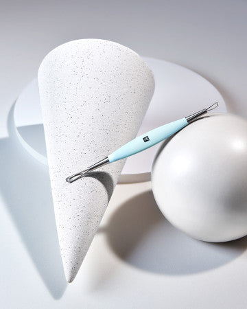 Darstellung eines ZWILLING Premium Mitesserentferners in mint auf artifiziell geformten Steinobjekten.