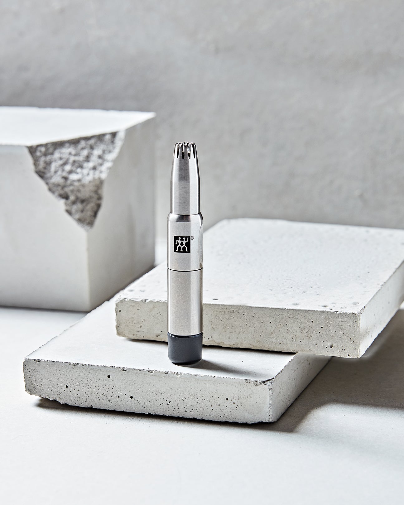 Darstellung des ZWILLING Premium Nasen- und Ohrenhaartrimmer aus rostfreiem Edelstahl auf Betonplatten.