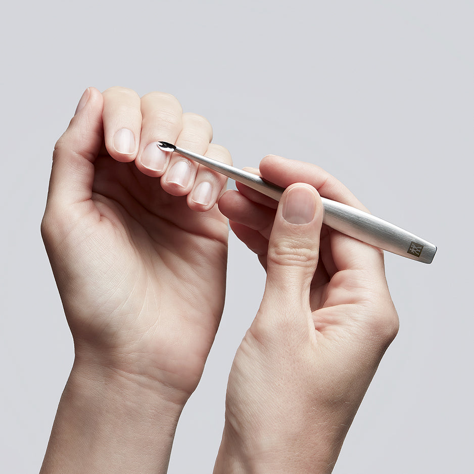 Anwendung des ZWILLING Premium Nagelhautmessers aus rostfreiem Edelstahl an der Nagelhaut des linken Mittelfingers.