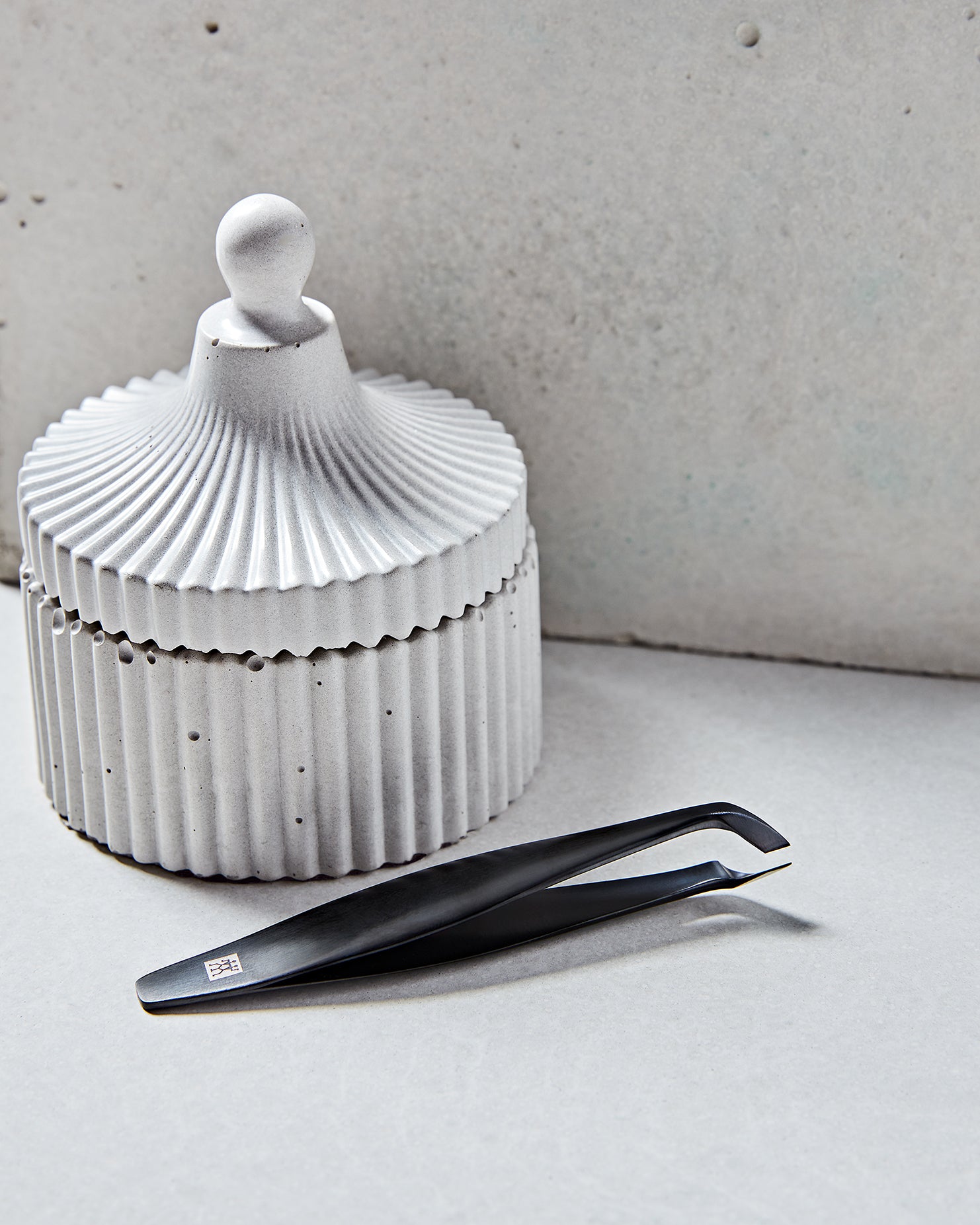 Darstellung des ZWILLING Premium Nagelhautschneiders in schwarz neben artifiziellen Betonobjekten.