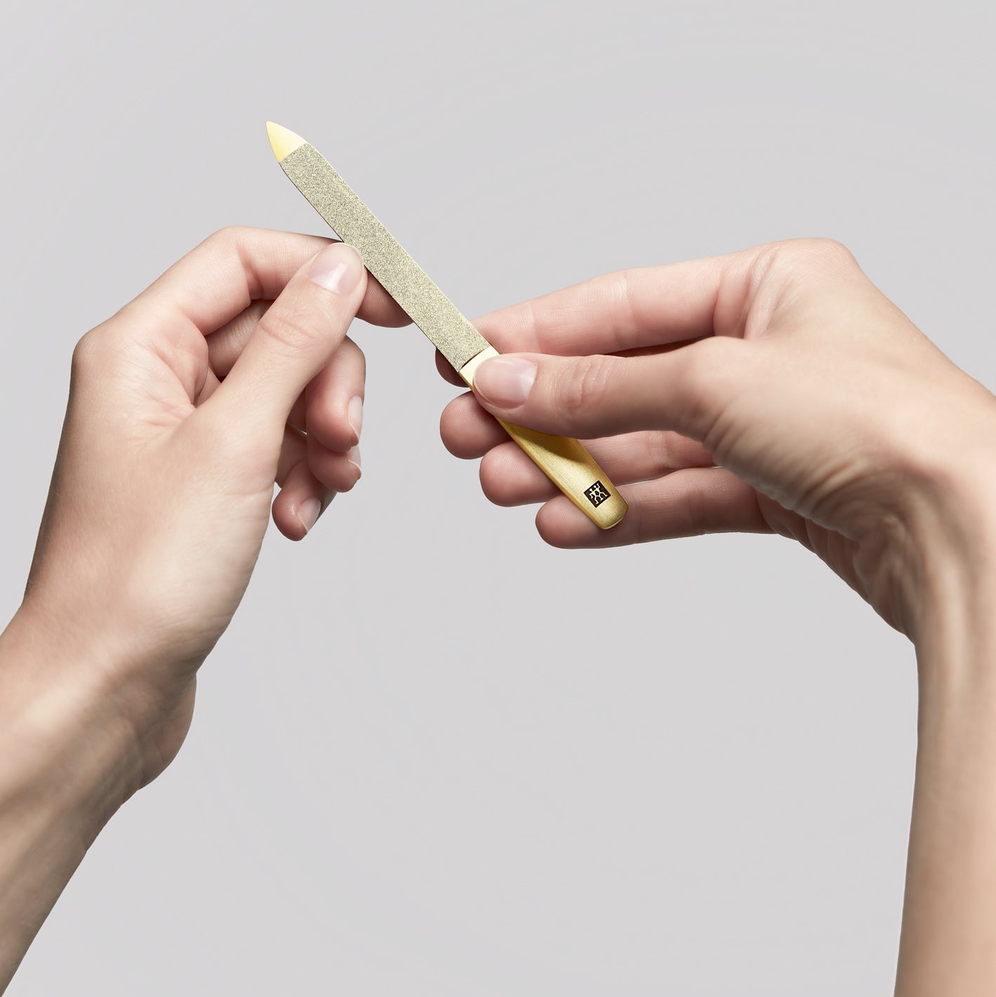 Anwendung einer ZWILLING Premium Saphir-Nagelfeile in Gold am linken Daumennagel.