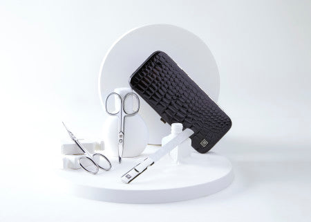 ZWILLING Premium-Produkte in Silber und schwarzes Etui auf Keramikobjekten drapiert.