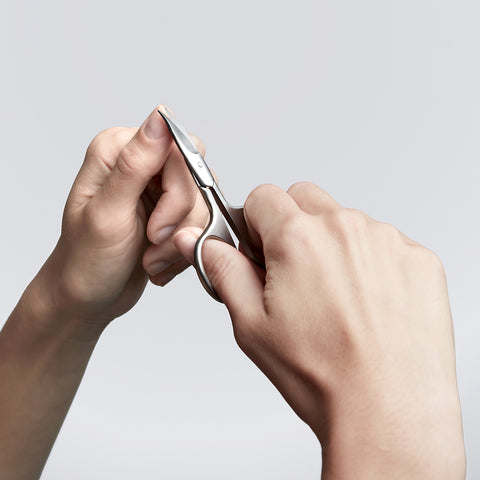Anwendung einer ZWILLING Premium Nagelhautschere aus rostfreiem Edelstahl am linken Daumennagel.
