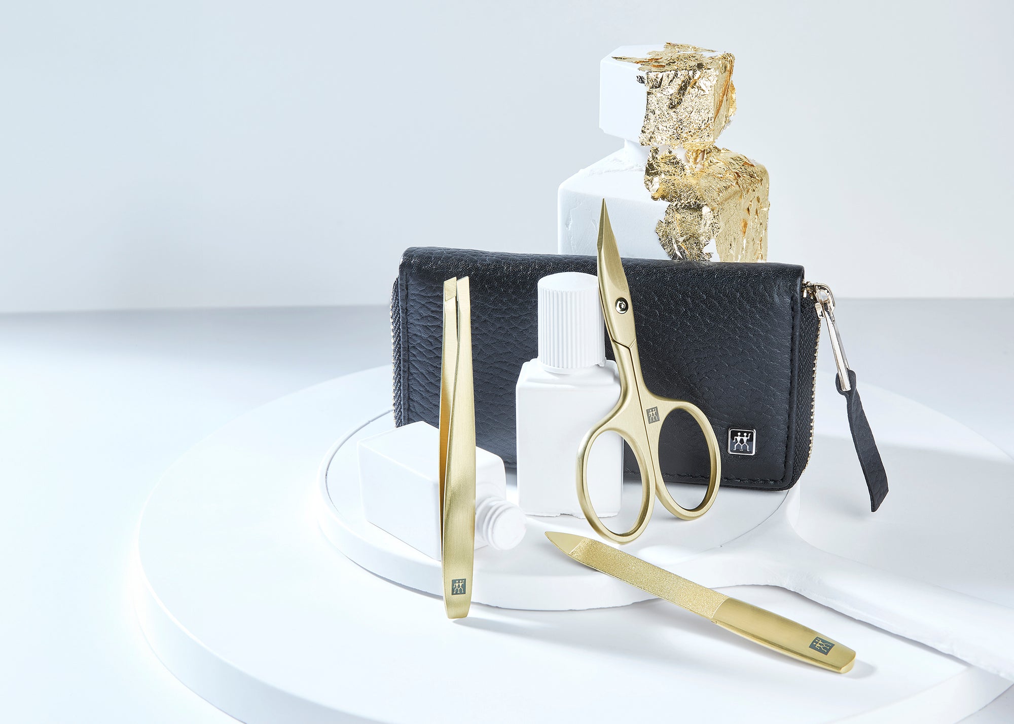 Darstellung eines ZWILLING Premium Maniküre Sets 3tlg. umgeben von artifiziellen Betonobjekten, veredelt mit Blattgold.