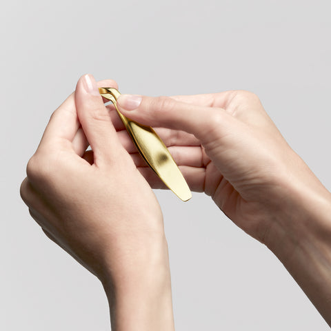 Anwendung eines ZWILLING Premium Nagelhautschiebers in gold an der Nagelhaut des linken Daumens.