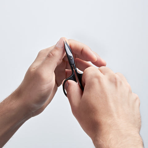 Anwendung einer ZWILLING Premium  Nagel- und Nagelhautschere in Schwarz am linken Daumen Fingernagel.