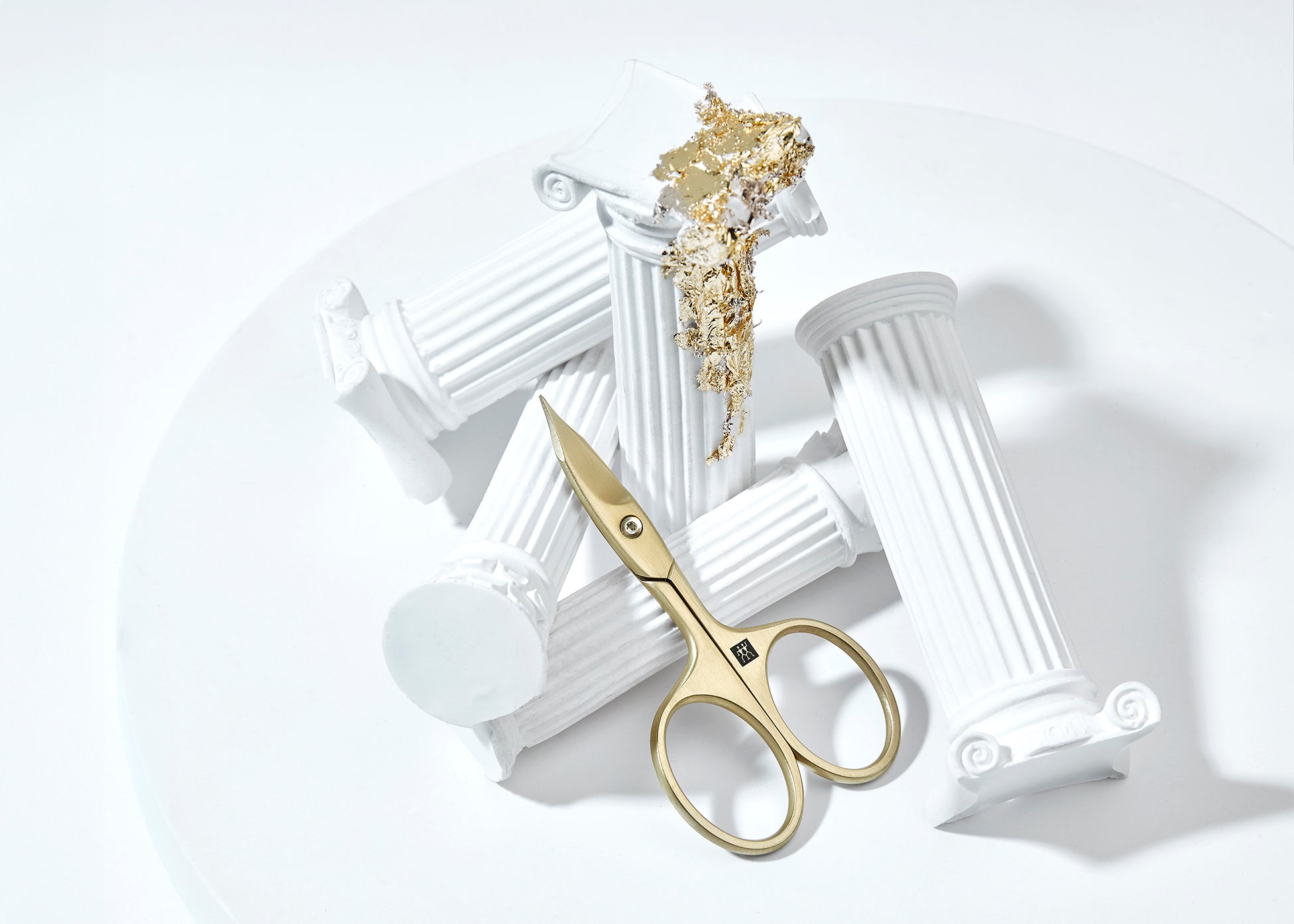 Sehr hochwertige Darstellung der ZWILLING Premium Nagel- und Nagelhautschere inmitten von artifiziellen Marmorsäulen mit Blattgold.