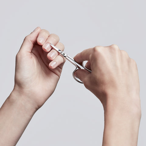 Anwendung einer ZWILLING Classic Nagelhautschere aus rostfreiem Edelstahl an der Nagelhaut des linken Mittelfingers.