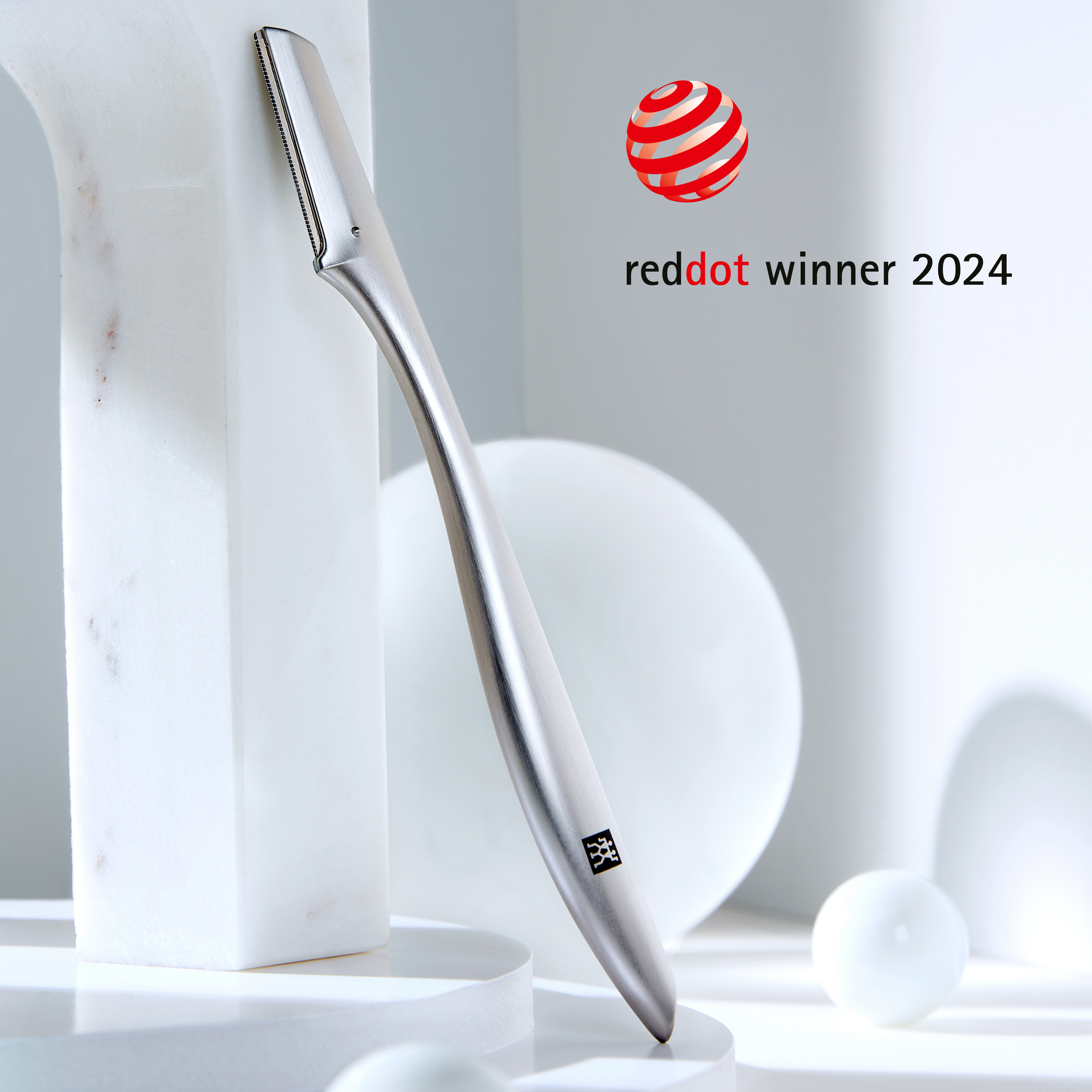 Darstellung des ZWILLING Premium Gesichtshaar-Rasierers inmitten von Marmorobjekten. Ausgezeichnet mit dem reddot winner award 2024.