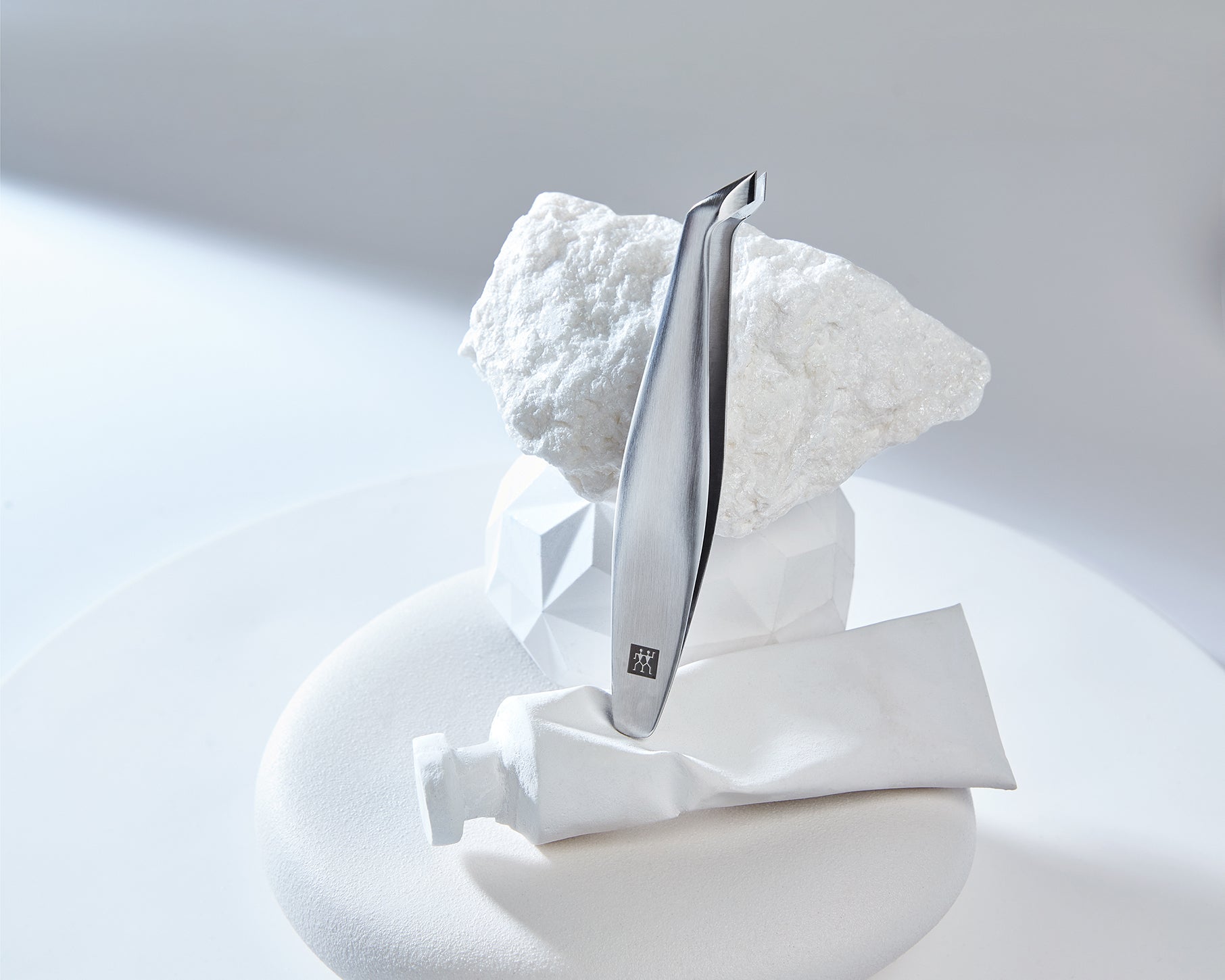 Darstellung des ZWILLING Premium Nagelhautschiebers aus rostfreiem Edelstahl positioniert auf diversen, artifiziellen Objekten.