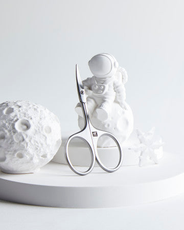 Sehr hochwertige Darstellung der ZWILLING Premium Baby-Nagelschere inmitten von blauen, verspielten Holzobjekten.