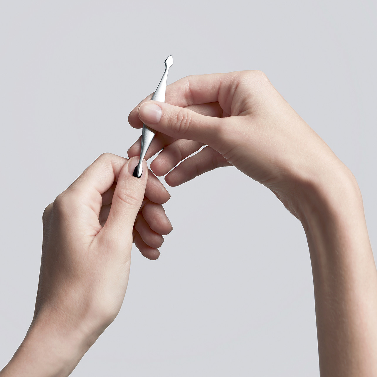 Anwendung des ZWILLING Premium Nagelhautschiebers und -reinigers aus rostfreiem Edelstahl am linken Daumennagelbett.